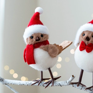 Pair of festive Christmas bird figurines with red scarves and hats on snowy branches