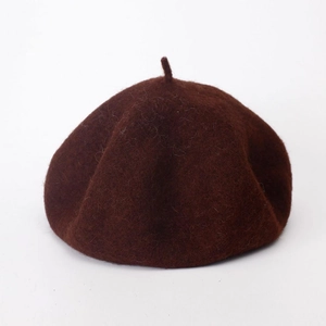 Close-up of deep brown wool beret showing premium felt texture on white background