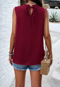 Detail view of red sleeveless high neck top featuring a back tie and dotted texture