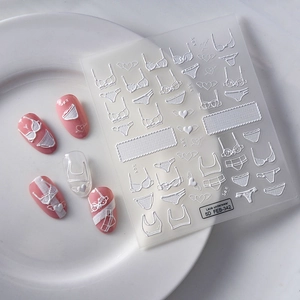 Detailed 5D embossed nail art stickers featuring white lace lingerie and heart patterns