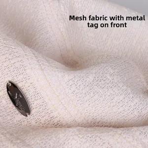 Macro view of lightweight lace mesh fabric and engraved oval metal tag on a summer hat