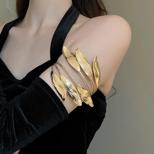 Macro detail of multi-layered golden leaf arm cuff bracelet on fashion model