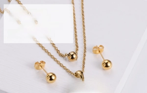 Detailed close-up of golden hollow heart tree pendant necklace and ball stud earrings