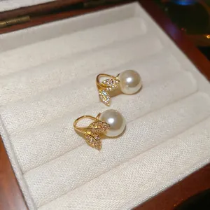 Elegant gold leaf earrings with sparkling zircons and white pearls in a jewelry box