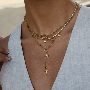 Gros plan d'un ensemble de colliers dorés multicouches avec pendentifs étoile et croix