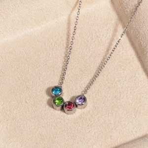 Gros plan du collier en argent avec quatre pierres précieuses rondes colorées sur velours