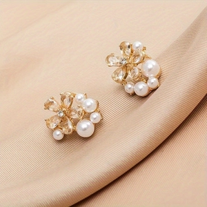 Elegant gold flower stud earrings with white pearls and sparkling zircons on pink silk
