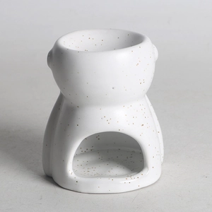Close-up of white ceramic essential oil burner with gold speckles in abstract human shape