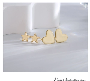 Detailed shot of gold plated star and heart stud earrings with water ripple light shadows