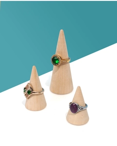 Detail view of gold and silver rings with green and purple gems on wooden cone stands