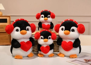 Group of plush penguin toys in four sizes with earmuffs and red hearts on a wooden desk