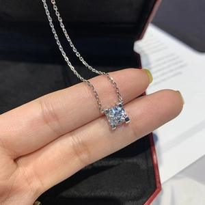 Detailed view of square cut zircon pendant on a silver chain held over a red box