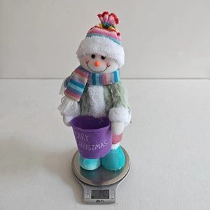 Detail view of colorful snowman plush decoration weighing 340.5g on a scale