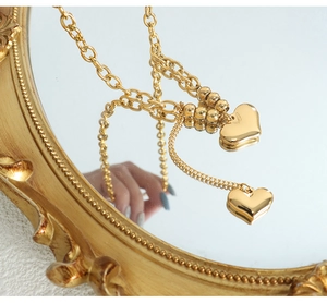 Detailed mirror reflection of double layered gold heart pendant necklace with metal beads