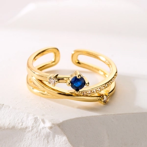 Irregular geometric gold ring with blue gemstone and sparkling zircon accents