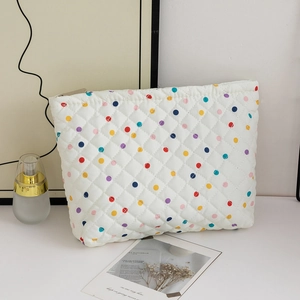Detail of white quilted makeup bag with colorful polka dots and metal zipper closure