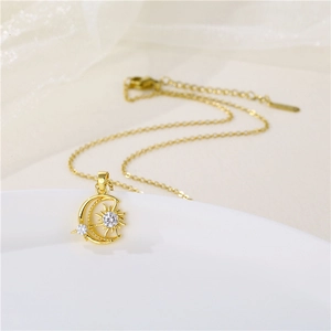 Gold celestial necklace with sun moon pendant and zircon stones on white ceramic tray