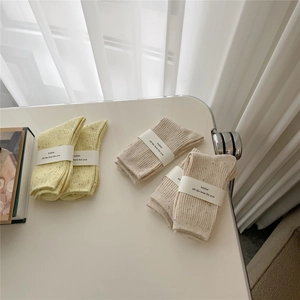 Detail of speckled cotton crew socks with ribbed cuffs and branded paper packaging wrap