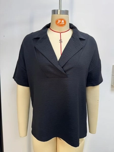 Detail of black short sleeve blouse showing notched lapel and textured crepe fabric