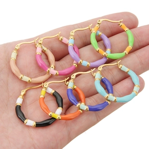 Set of seven bohemian rainbow enamel bamboo style hoop earrings held in a hand