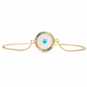 Macro detail of 18K gold Evil Eye bracelet with rainbow cubic zirconia and blue pupil inlay