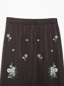 Détail de la taille élastique avec perles florales et broderies de sequins verts