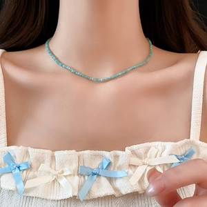Gros plan d'un collier de perles géométriques bleu clair porté sur le cou pour le détail