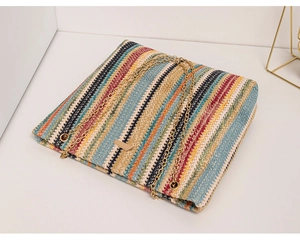 Detail of colorful woven straw bucket bag with gold chain strap and striped pattern