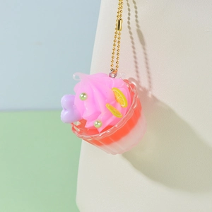 Miniature cupcake keychain with pink cream and fruit decor on a golden chain strap