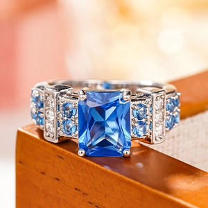 Macro shot of rectangular blue zircon ring with vintage four-claw setting and pavé side stones