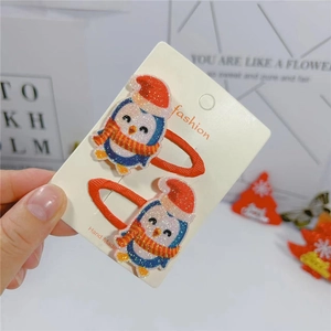 Cute Christmas penguin hair clips with red hats and sequins on a display card