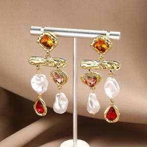 Macro detail of baroque pearl earrings with rhinestones and multi-colored gemstones