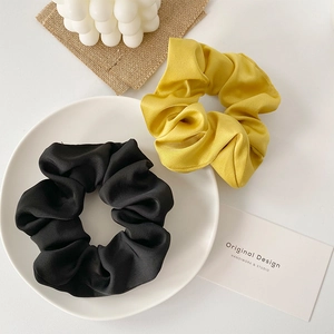 Detail of black and yellow satin scrunchies with silk texture on a white decorative plate