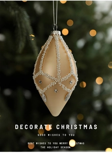 Close-up of elegant beige Christmas ball ornament with white beads and rhinestones