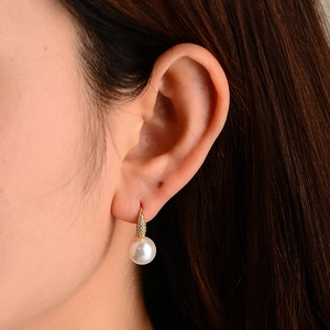 Detailed close-up of a pearl drop earring with a shimmering gold diamond-studded clasp