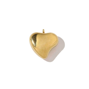 Détail d'un pendentif coeur en acier inoxydable doré poli sur un fond blanc épuré