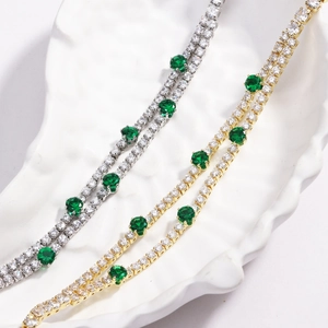 Macro shot of gold and silver tennis bracelets with white zircon and green emerald stones