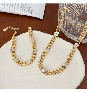 Macro shot of gold-plated chain set with rhinestone heart charms on a tray
