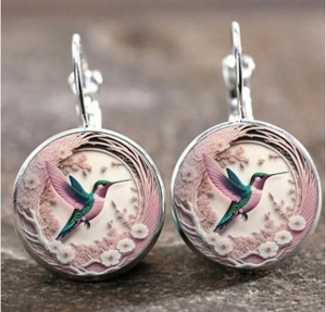 Detailed macro view of silver earrings featuring a colorful hummingbird and floral design