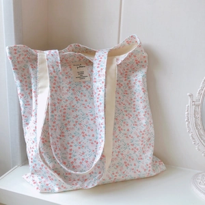 Detail of floral canvas tote bag showing delicate pink flowers and textile label