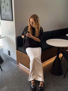Schwarzes lockeres Damen T-Shirt aus Baumwolle mit langem weißem Satinrock im modernen Café