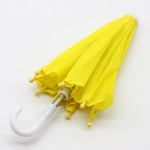 Detailed view of a closed yellow mini umbrella for 18-inch dolls with white curved handle