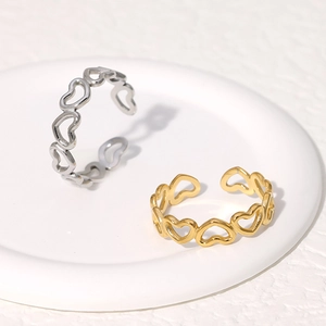 Detail of gold and silver heart-shaped cutout rings on a white ceramic display tray