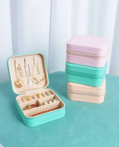 Detail view of portable jewelry boxes in mint green, pink, and beige with zip closure