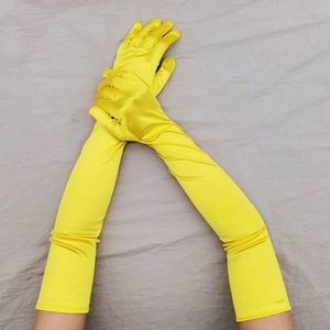Dettaglio di guanti lunghi in raso giallo brillante per abiti da sera eleganti anni '20