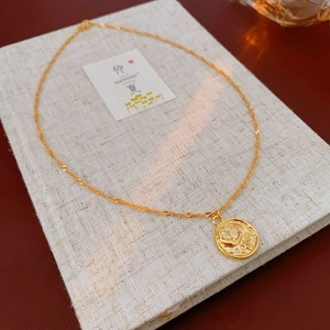 Macro shot of gold coin pendant with moon and star relief and zircon inlay