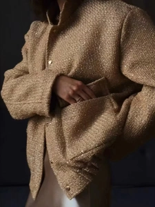 Detail of gold tweed jacket featuring metallic buttons and textured fabric finish