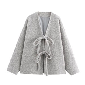 Detail of grey plush cardigan featuring ribbon bow ties and textured fabric finish