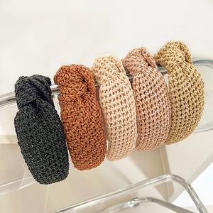Détail de cinq serre-têtes tressés avec nœud en noir, marron, beige, rose et jaune