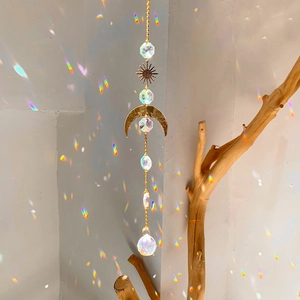 Detail of sun and moon crystal suncatcher casting rainbow light on a white wall